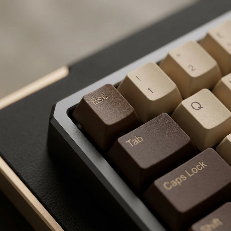 Close-up of a mechanical keyboard showing dark brown and cream keycaps with a dark gray frame and a beige side accent.