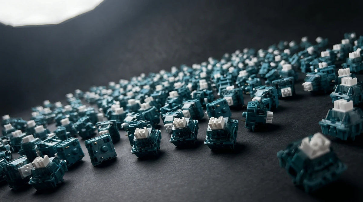A close-up, angled view of numerous teal and white mechanical switches densely packed on a dark, textured surface with dramatic lighting.