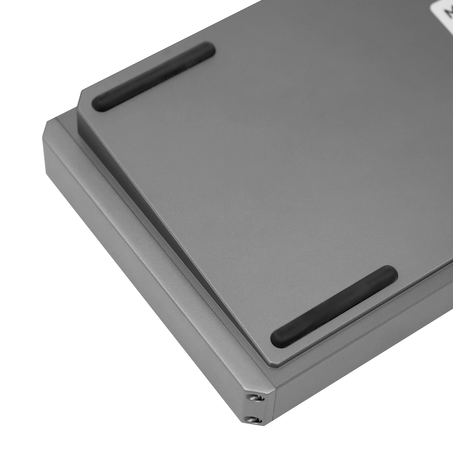 Close-up of a gray rectangular electronic device or enclosure with rounded corners and two black rubber feet on the top surface, shown on a white background.