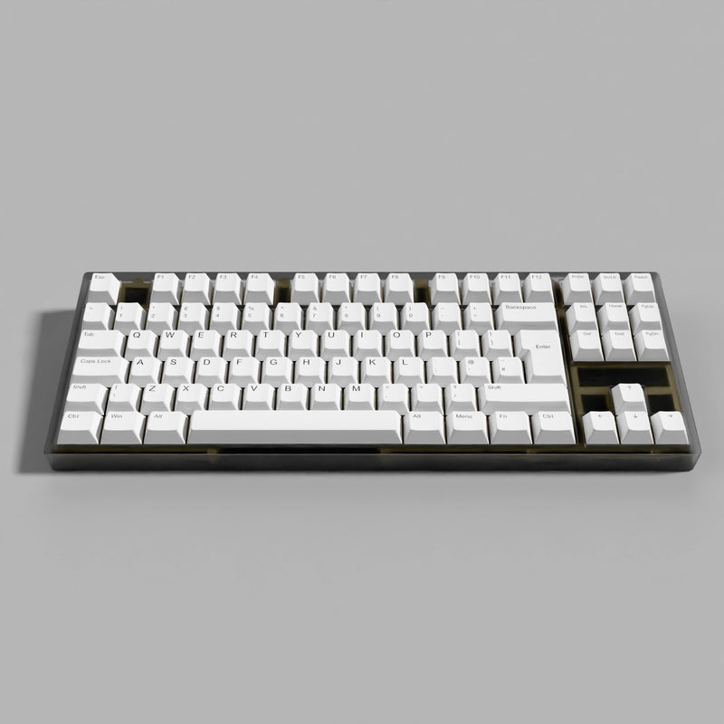 A mechanical keyboard with white keycaps and a dark gray to black frame, shown from a top-down perspective on a neutral gray background.